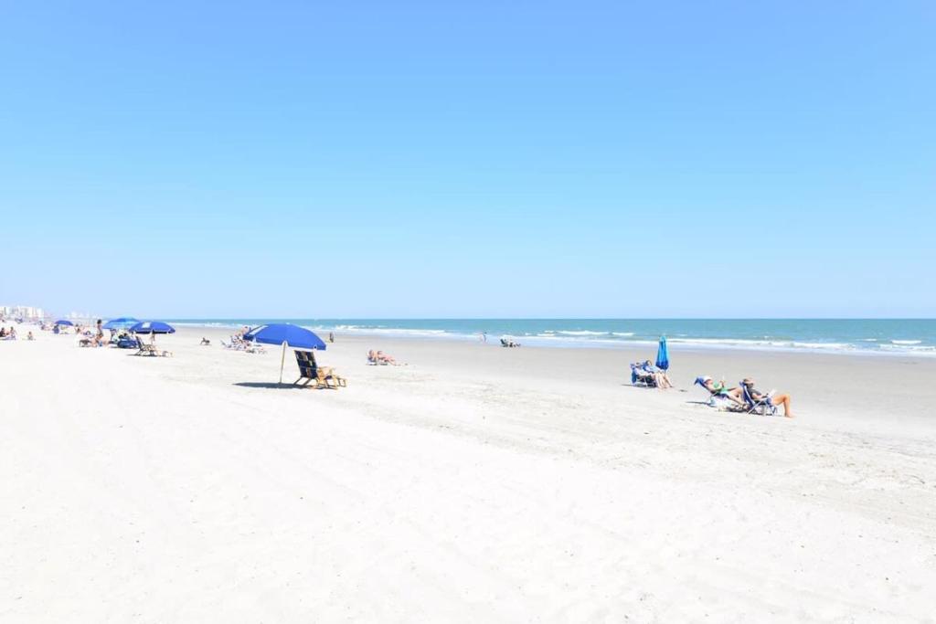 a group of people sitting on the beach at Oceanfront TOP LOCATION MODERN RESORT Lazy River Huge Pool Oasis in Myrtle Beach