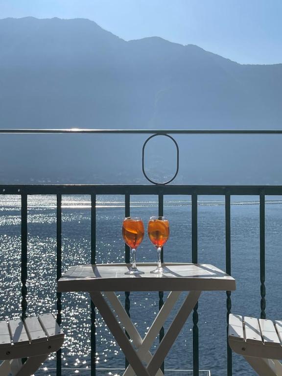 two wine glasses sitting on a table on a balcony at Holiday Home by the Beach in Sala Comacina