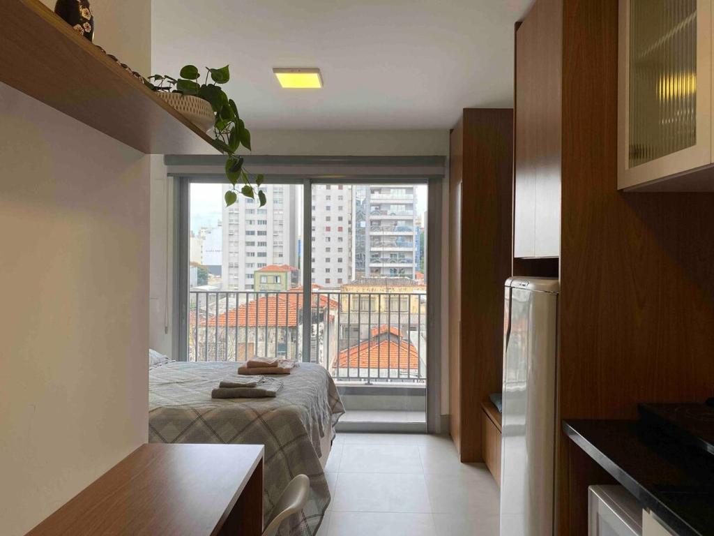 um quarto com uma cama e uma janela grande em Studio em Pinheiros a uma quadra da Faria Lima em São Paulo