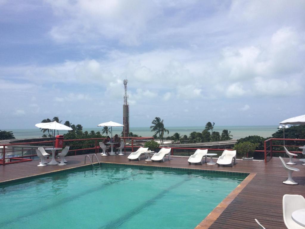 a swimming pool with chairs and a view of the ocean at VICTORY BUSINESS FLAT TAMBAU in João Pessoa