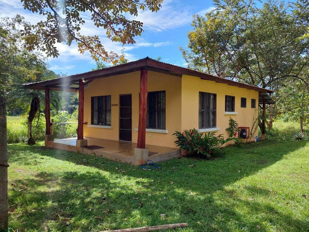 a small yellow house in a grass field at Costa Rica Getaway in Jacó