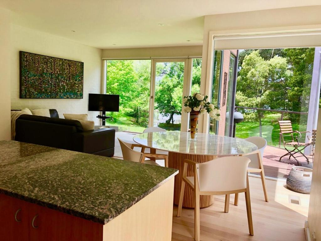 cocina y sala de estar con mesa de cristal en Lake Daylesford Villa2 Lake frontage pet friendly, en Daylesford