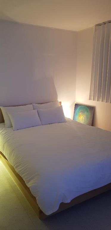 a large white bed in a room with a light at Dodam Stay in Seoul