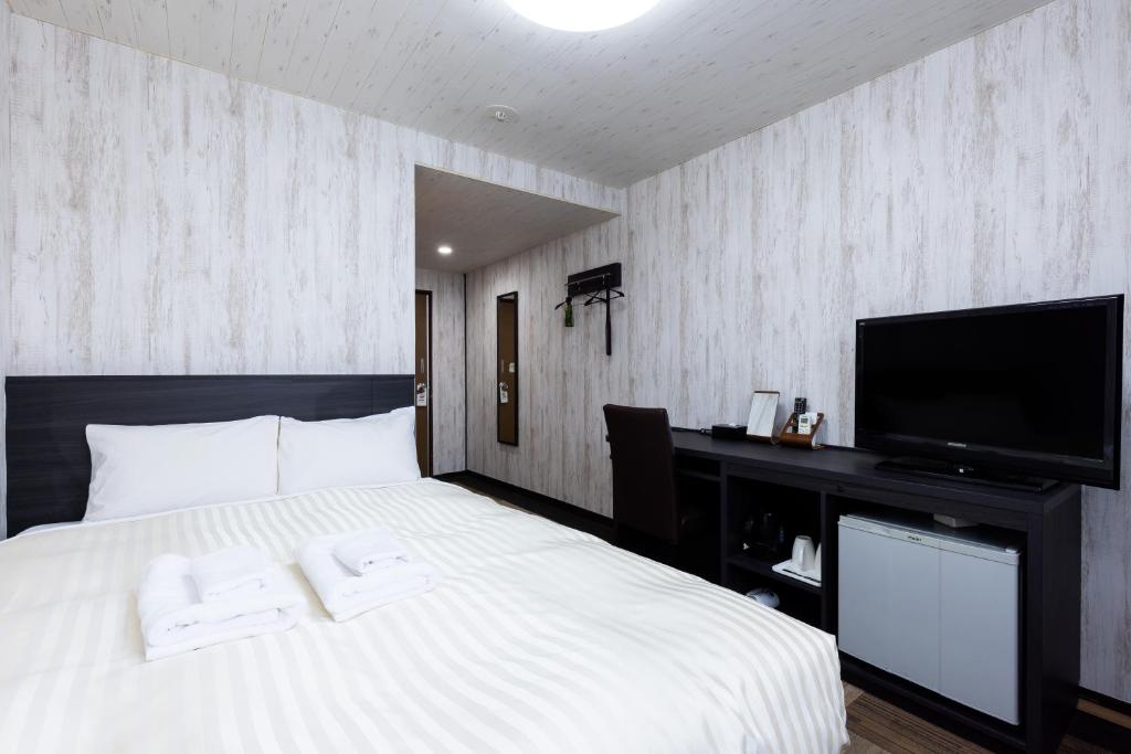 a bedroom with a white bed and a flat screen tv at Select Inn Fujisan Gotemba in Gotemba