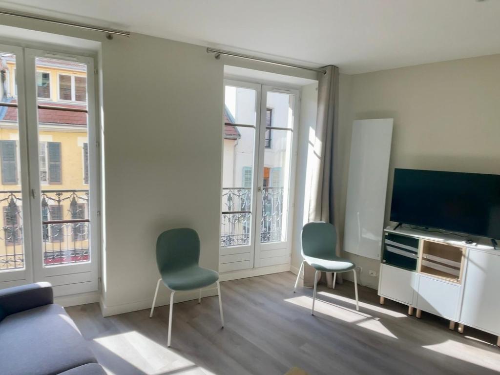 - un salon avec deux chaises et une télévision à écran plat dans l'établissement Studio cosy centre Aix-les-Bains avec wifi et animaux acceptés - FR-1-555-106, à Aix-les-Bains