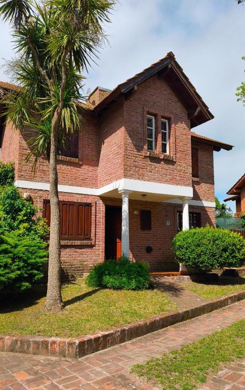 ein Backsteinhaus mit einer Palme davor in der Unterkunft Dúplex Complejo “Poker” in Villa Gesell