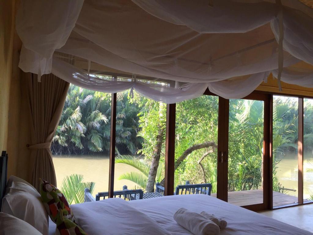 a bedroom with a bed and a large window at Bangsrai Cottage in Suratthani