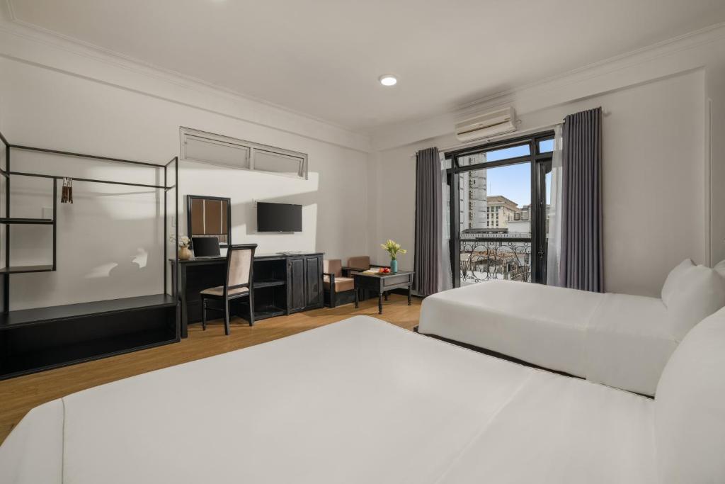 Una habitación de hotel con dos camas y un escritorio. en KLY Boutique Hotel Hue, en Hue