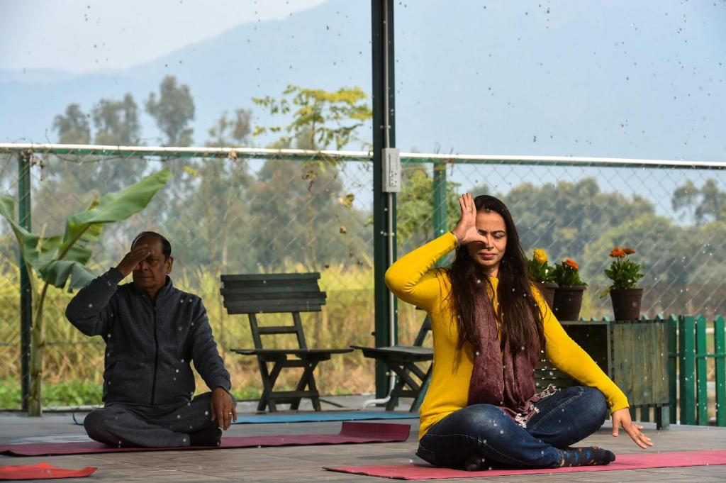 a man and a woman sitting on the ground at Sukoon - A Wellness Resort, Uttarakhand in Chūharpur