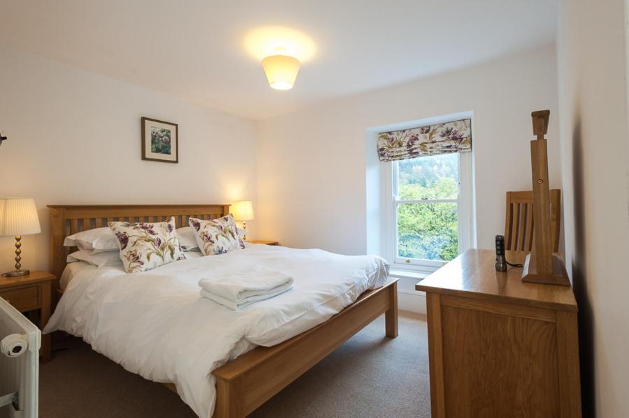 Bronfelin & Troed-y-Rhiw Holiday Cottage في لانْوُرتيد ويلز: غرفة نوم بسرير كبير ونافذة