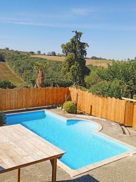- une piscine dans un jardin avec une clôture en bois dans l'établissement La glycine, à Verfeil