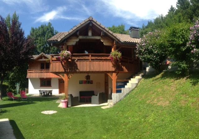une grande maison avec une terrasse sur une pelouse verdoyante dans l'établissement Appartement dans les aravis, proche du Grand Bornand et de la Clusaz, à Entremont