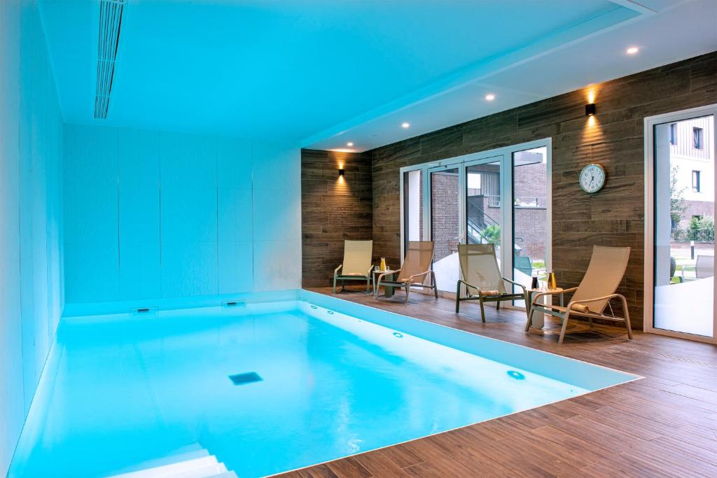 - une grande piscine dans une maison à l'éclairage bleu dans l'établissement Les Boréales - Appart'hotel & Restaurant, à Rouen
