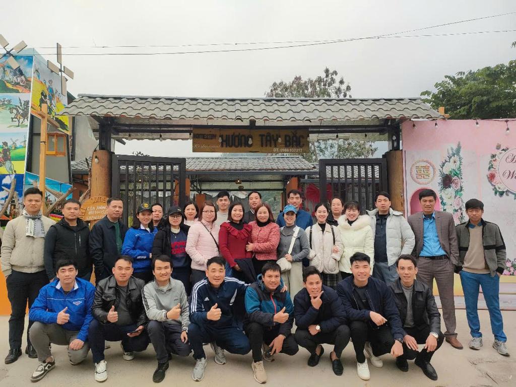 a group of people posing for a picture in front of a building at Nhà hàng Homestay Hương Tây Bắc in Trạm Tấu