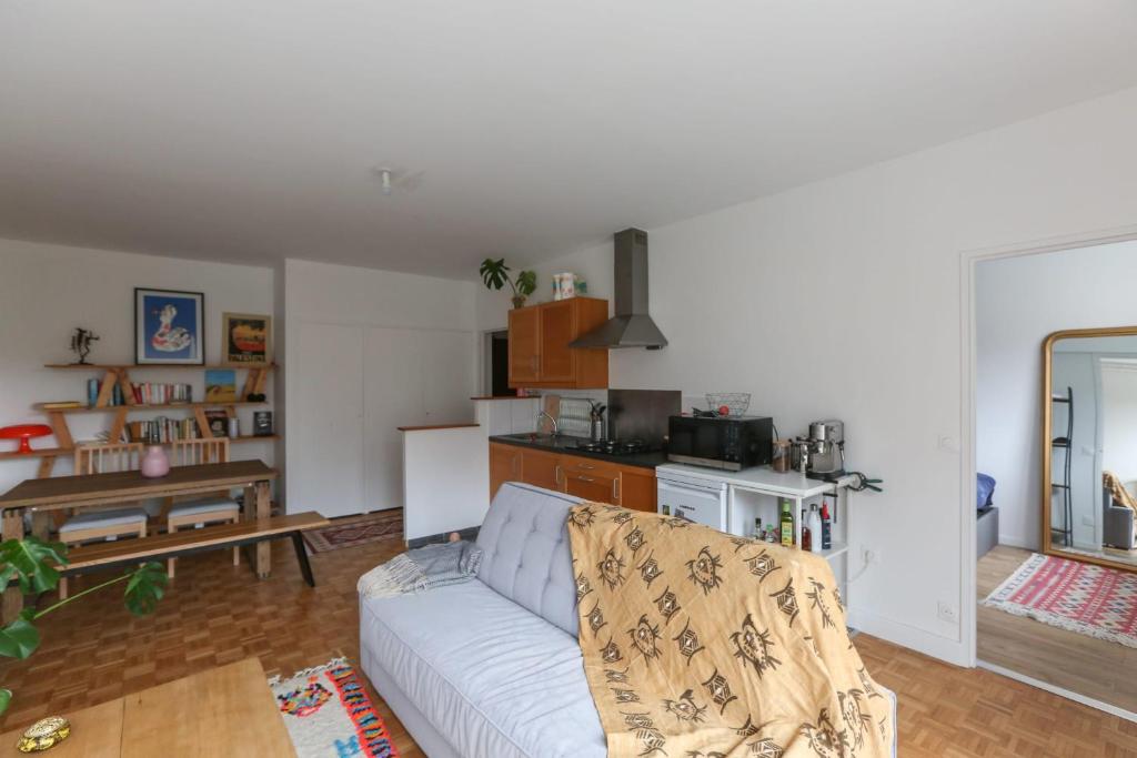un salon avec un canapé blanc et une cuisine dans l'établissement Charming apartment in Buttes Chaumont, à Paris