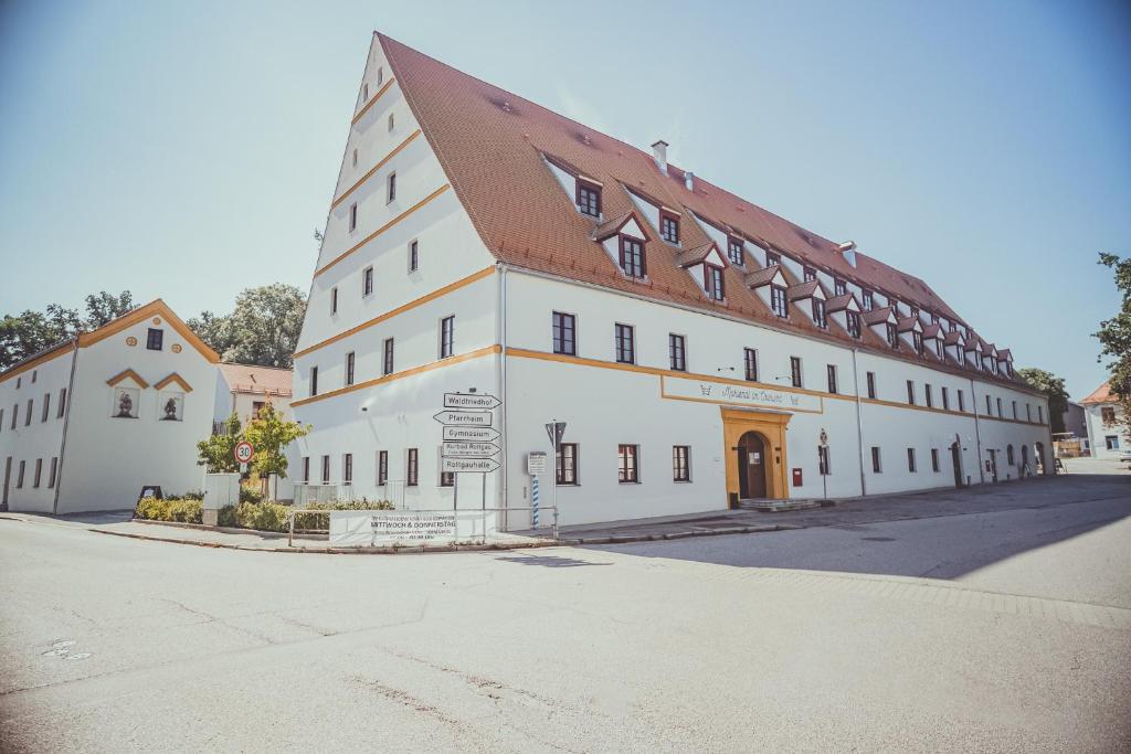ein großes weißes Gebäude mit einem braunen Dach in der Unterkunft Mariandl im Oberwirt in Eggenfelden