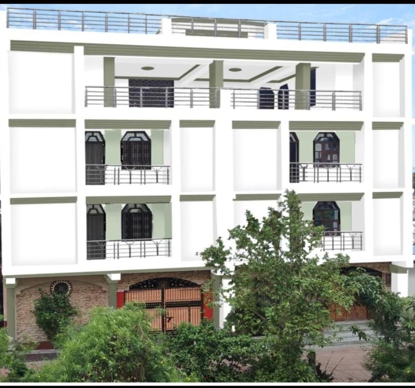un edificio blanco con balcones y árboles delante de él en Anand Homestay, en Bodh Gaya