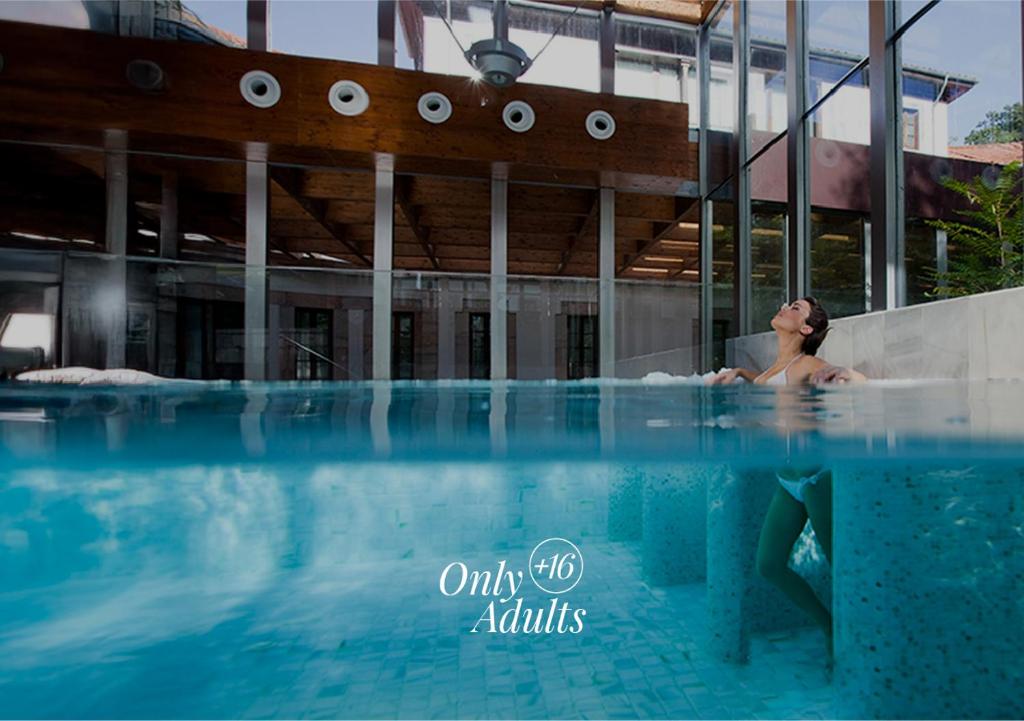 una mujer en una piscina en un edificio en Gran Hotel Las Caldas by blau hotels - Adults Only, en Las Caldas