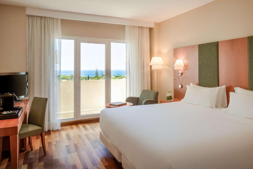 a hotel room with a large bed and a large window at NH Collection Marbella in Marbella