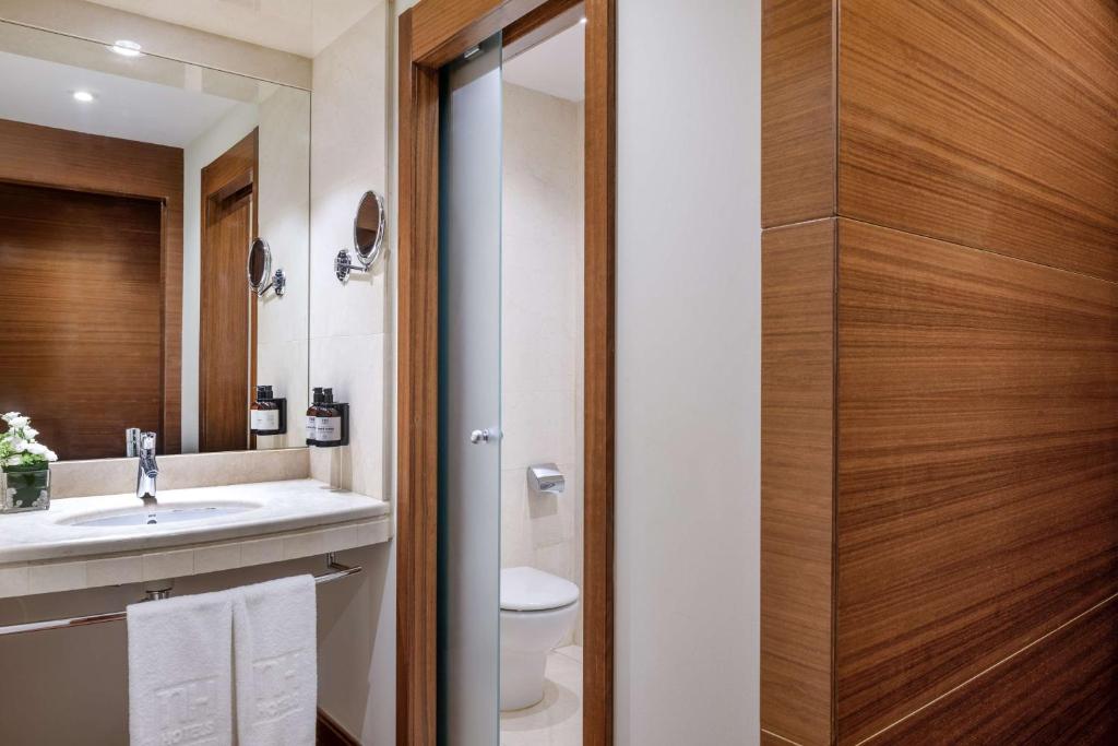 a bathroom with a sink and a toilet and a mirror at NH Collection Marbella in Marbella