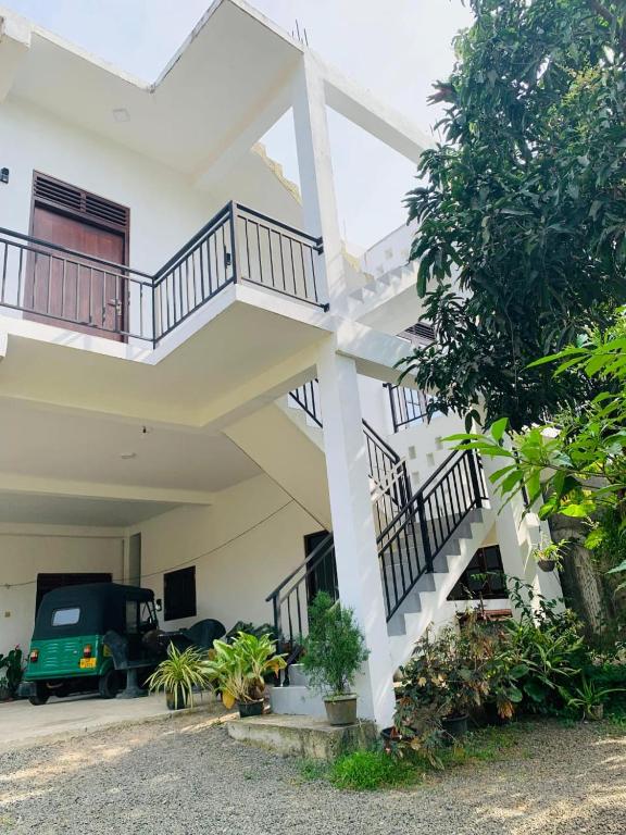 a white house with stairs and a car in the driveway at AQUARIUS Stay in Tangalle