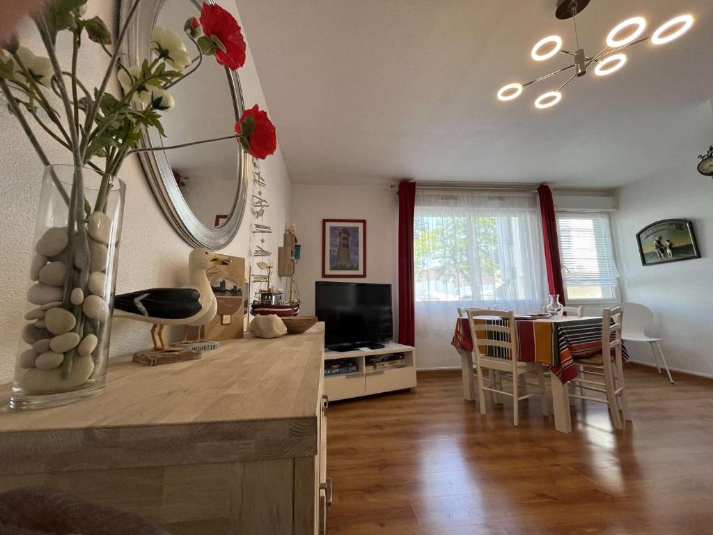 un salon avec une table avec un vase de fleurs dans l'établissement Appartement T2 LA ROCHELLE - LR640-041, à La Rochelle