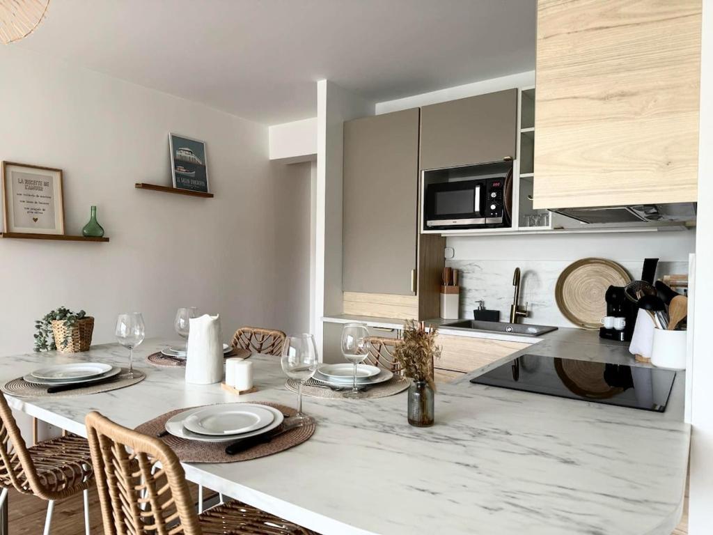 une cuisine avec une table avec des assiettes et des verres à vin dans l'établissement Joli Appartement avec terrasse Bassin d'Arcachon, à Gujan-Mestras