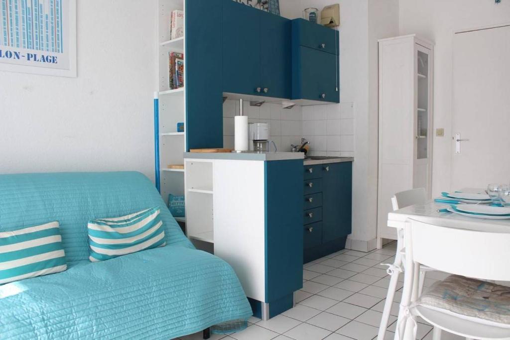 Una cocina con gabinetes azules y un sofá azul. en Appt 2 pièces CHATELAILLON PLAGE - CL040-309, en Châtelaillon-Plage
