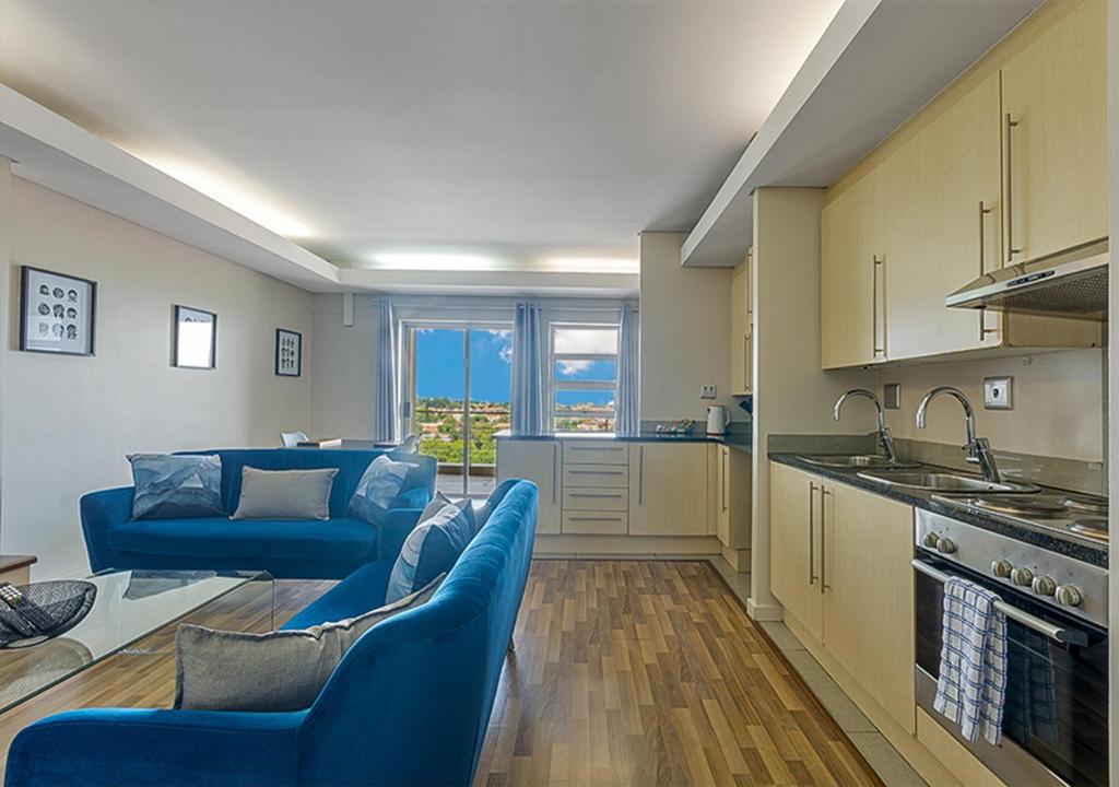 a living room with blue couches and a kitchen at Stylish Genisis on Fairmount U15 in Johannesburg
