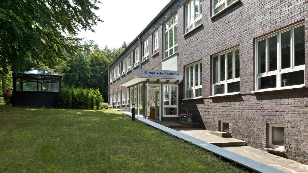 ein großes Backsteingebäude mit einem Rasenplatz davor in der Unterkunft Seminarhaus Europäische Akademie in Waren (Müritz)