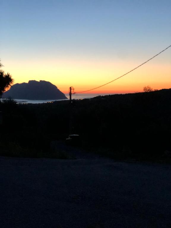 a sunset over a field with a mountain in the background at Casa Azzurra in Porto San Paolo