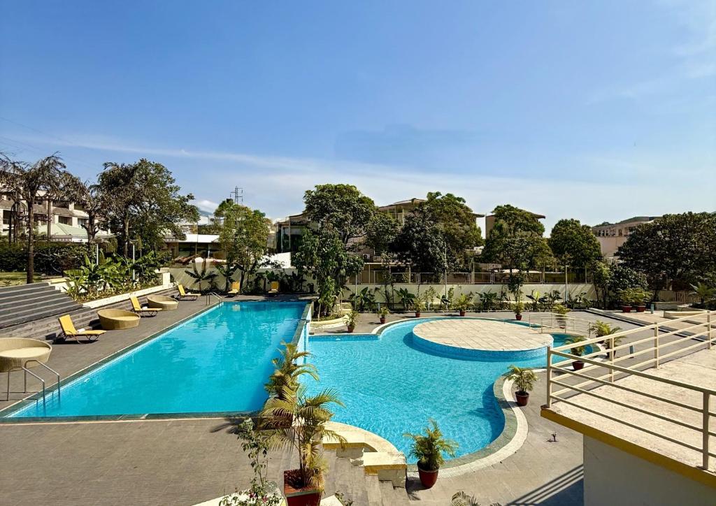 een groot zwembad met stoelen en bomen in een gebouw bij Camel Valley Resort & Spa, Igatpuri in Igatpuri