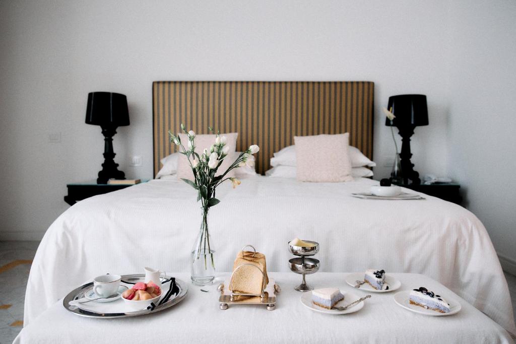 a bed with two plates of food and a vase of flowers at Palazzo del Corso – Boutique Hotel in Gallipoli