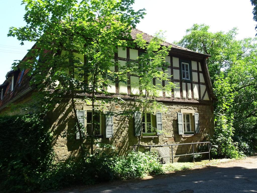 an old stone house with trees in front of it at Wohnung im Kutscherhaus in Wetzhausen