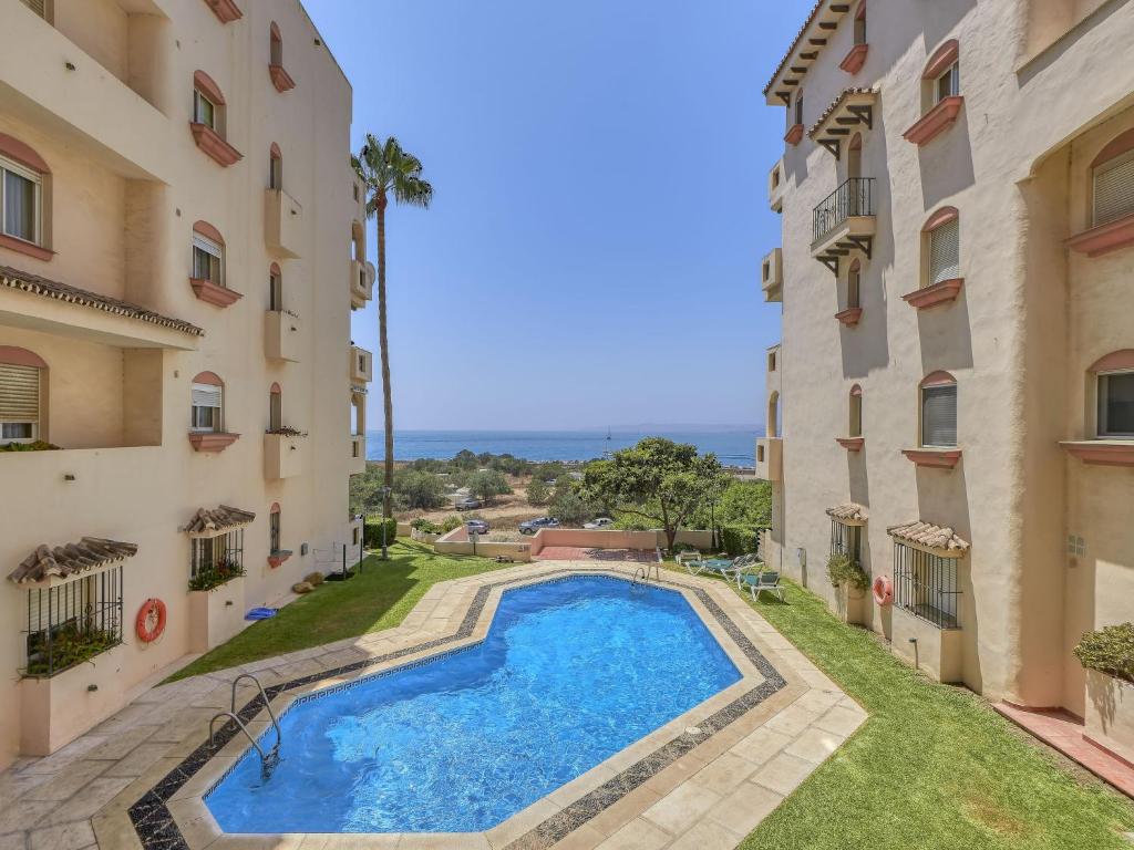an apartment with a swimming pool between two buildings at Apartment Marina Bay-1 by Interhome in Estepona