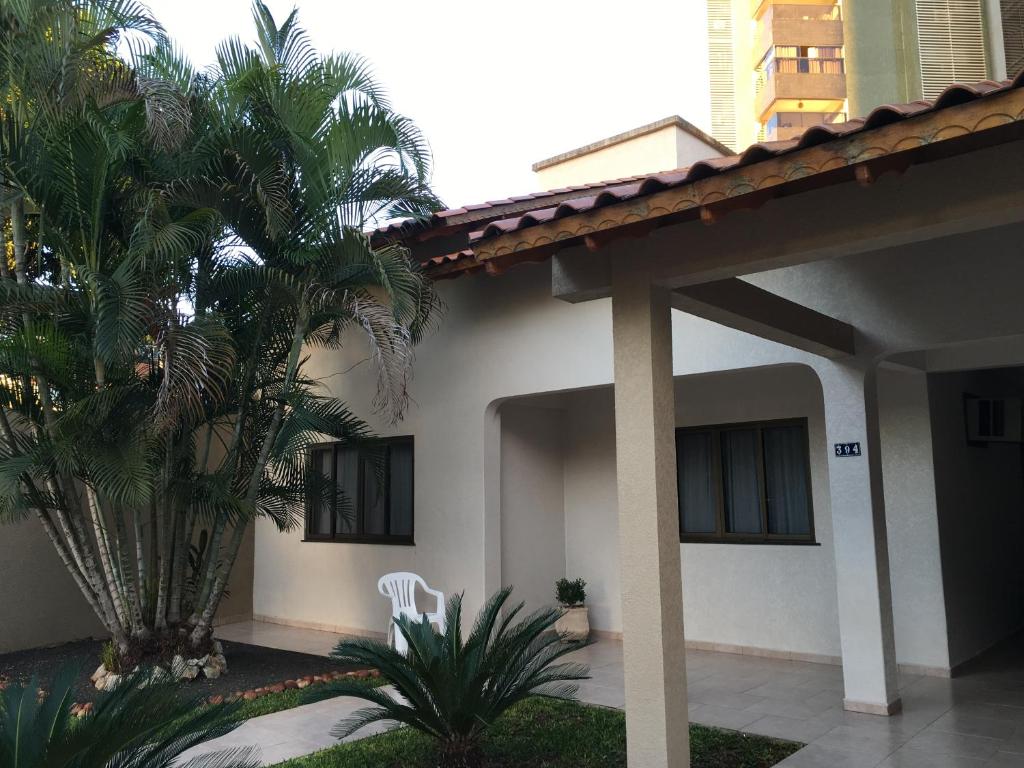 a house with palm trees and a white chair at Studio Julio Cezar in Foz do Iguaçu