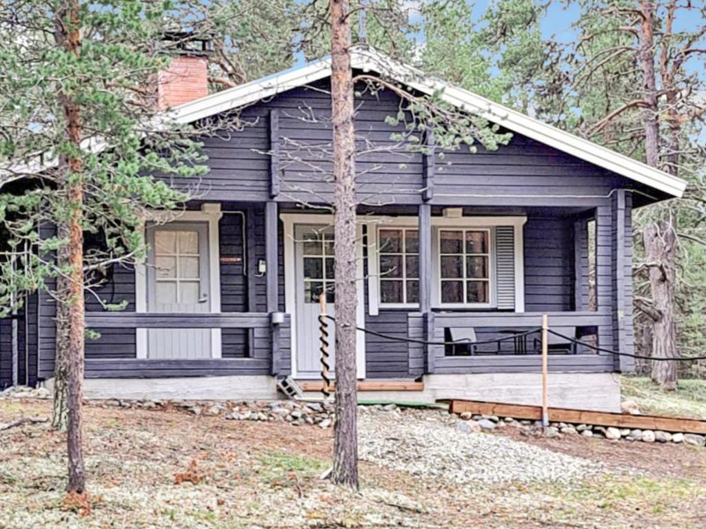 a small black house with a porch in the woods at Holiday Home Tunturitupa kuolpuna by Interhome in Raattama