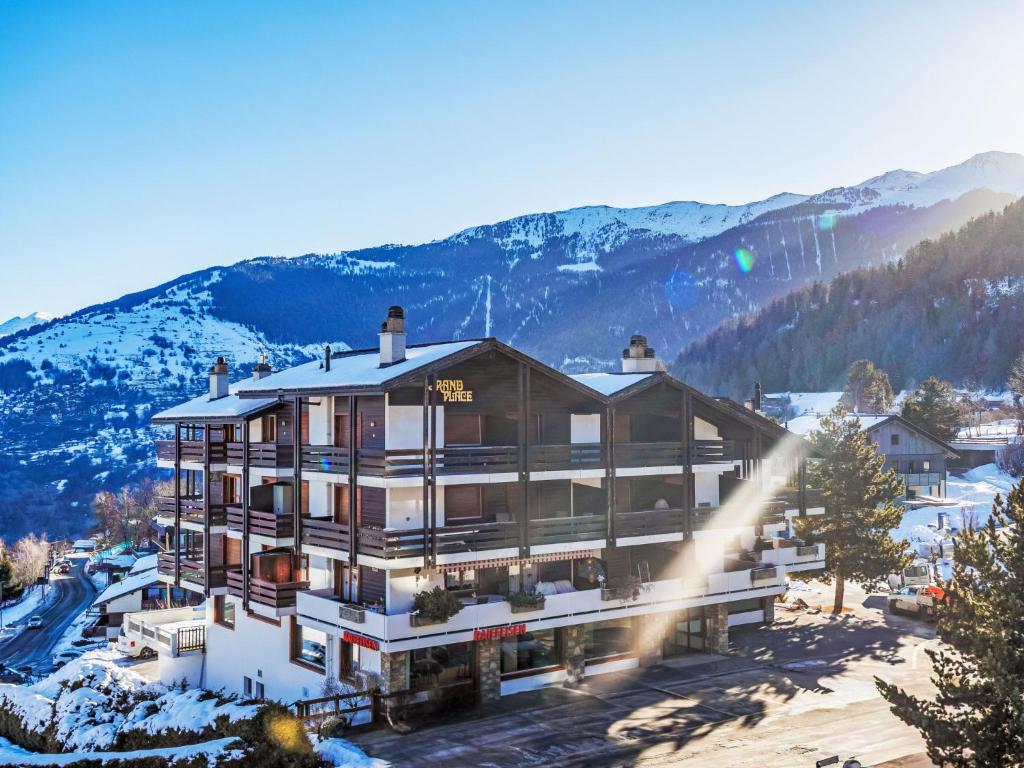 a building in the snow with mountains in the background at Apartment Grand Place 5 by Interhome in Nendaz