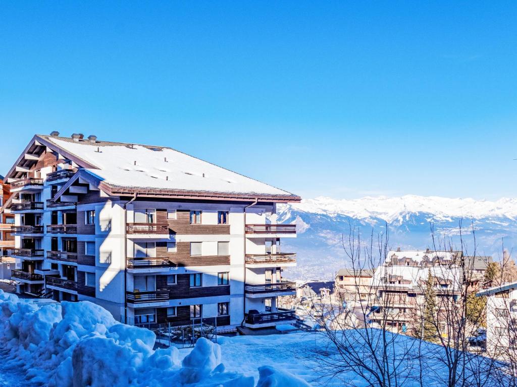 a building in the snow with mountains in the background at Apartment Valaisia 24A by Interhome in Nendaz