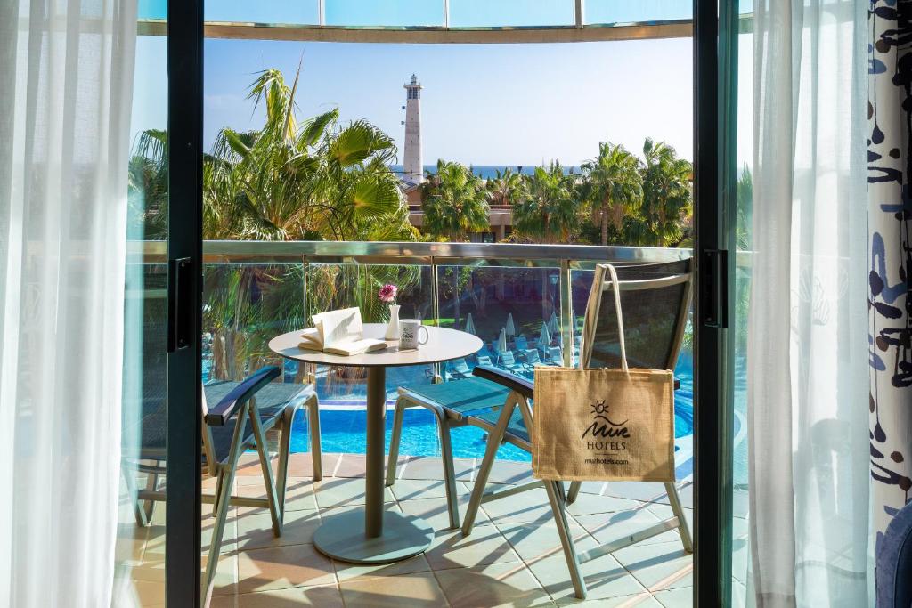 a table and chairs on a balcony with a view of a pool at MUR Faro Jandia Fuerteventura & Spa in Morro del Jable