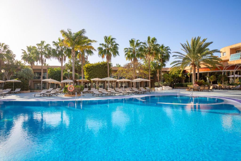 a large swimming pool with palm trees and umbrellas at MUR Faro Jandia Fuerteventura & Spa in Morro del Jable
