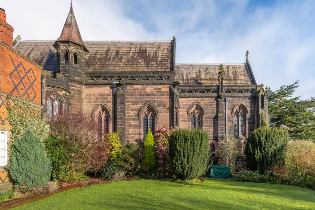 an old brick church with a grass yard at East House in High Legh