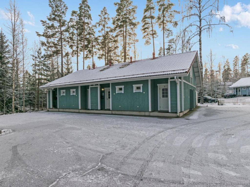 a green building in a parking lot with trees at Holiday Home Kylpylän ullanrinne 12 d by Interhome in Ikaalinen