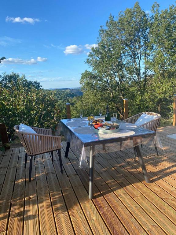 a table and two chairs on a wooden deck at Le Refuge des libellules in Daglan
