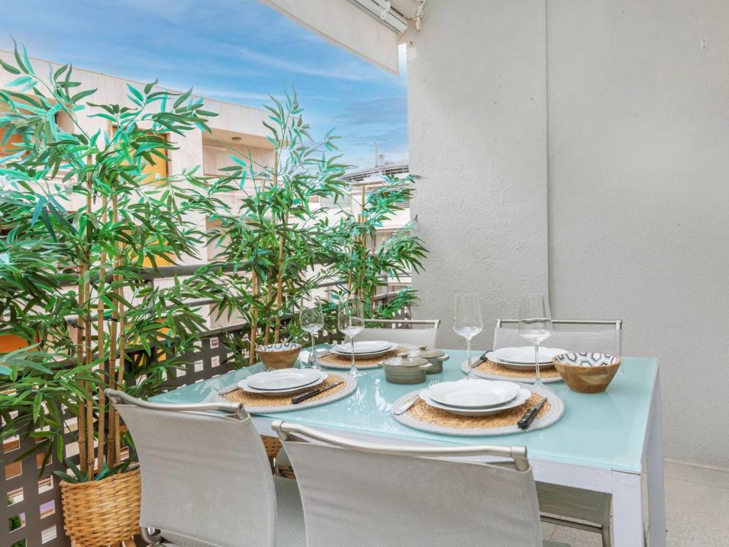 a table with white chairs and a blue table with plates at Apartment Serenity by Interhome in Tossa de Mar