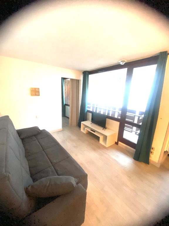 un salon avec un canapé et une grande fenêtre dans l'établissement Charmant appt 2 Ch St Jacques, à La Plagne Tarentaise