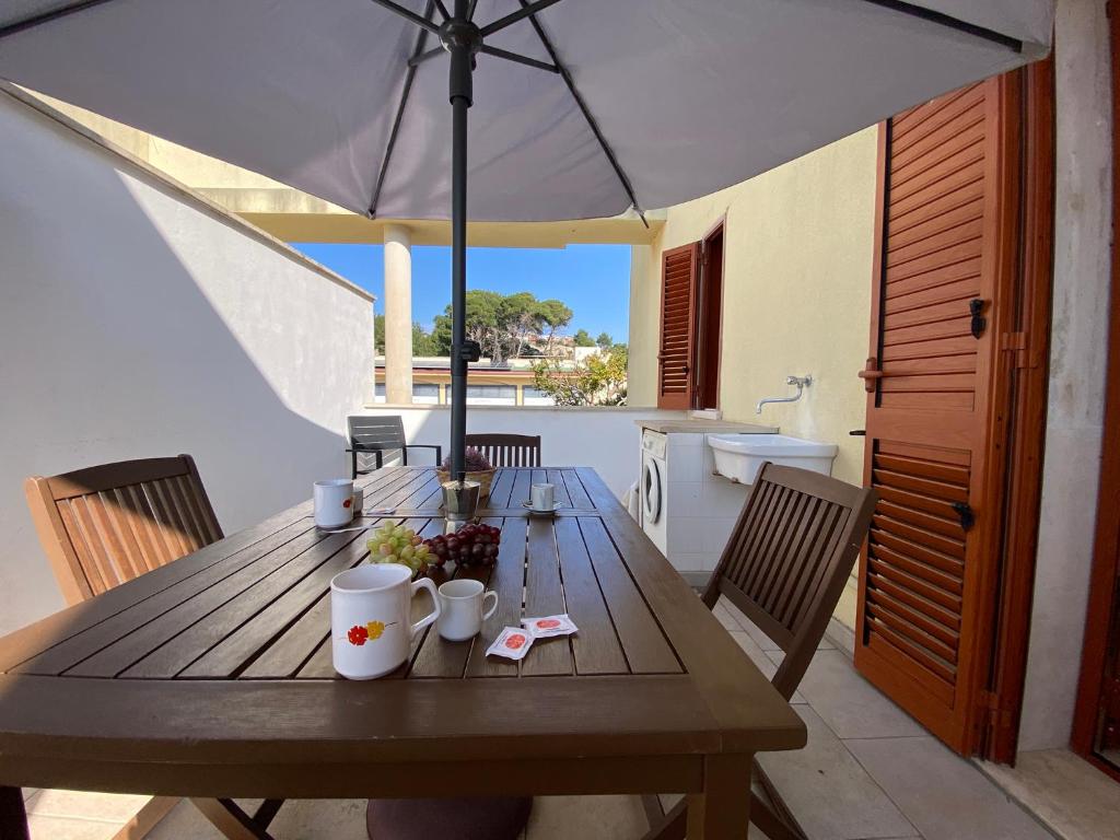 a wooden table with an umbrella on a patio at Armonia Machiavelli House Gallipoli in Gallipoli