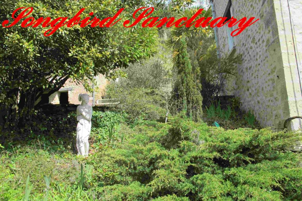 un jardin avec une statue sur l'herbe dans l'établissement Songbird Sanctuary, à Civray-de-Touraine