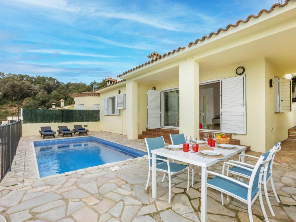 eine Terrasse mit Tisch und Stühlen und einem Pool in der Unterkunft Holiday Home El Moli-1 by Interhome in Tossa de Mar