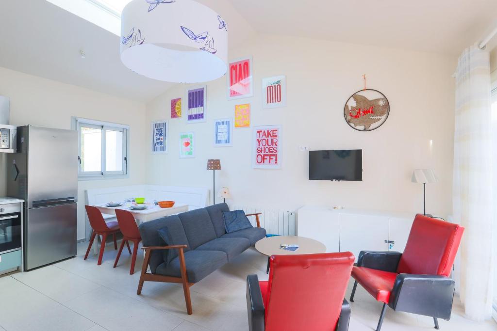 - un salon avec un canapé bleu et des fauteuils rouges dans l'établissement Maison Fantasio - Welkeys, à Dolus-d'Oléron